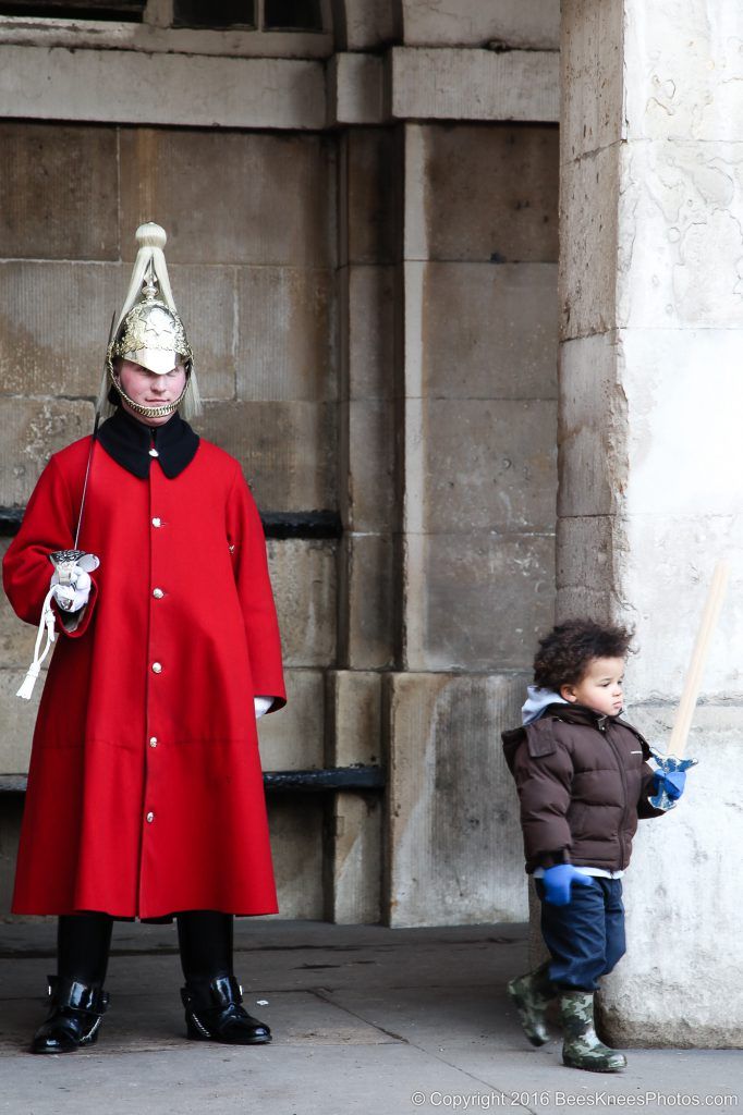 a young boy and a soldier standing guard in london