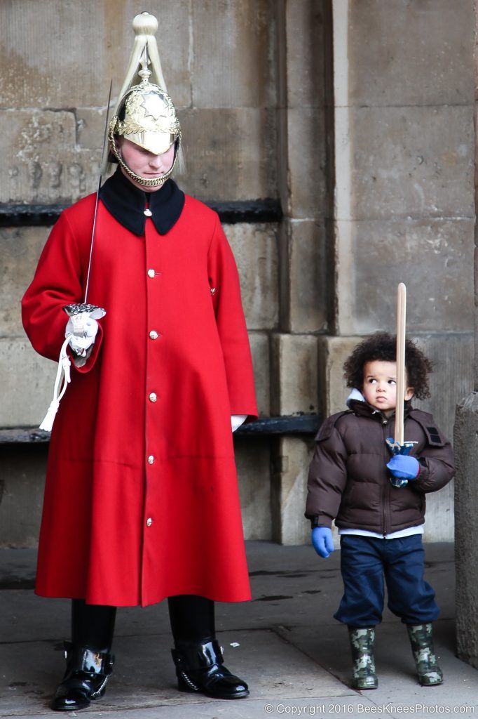 a young boy and a soldier standing guard together in london