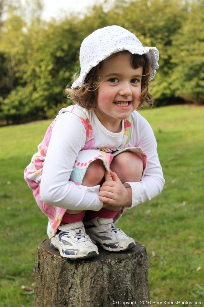 a young girl sat on a tree stump in the park