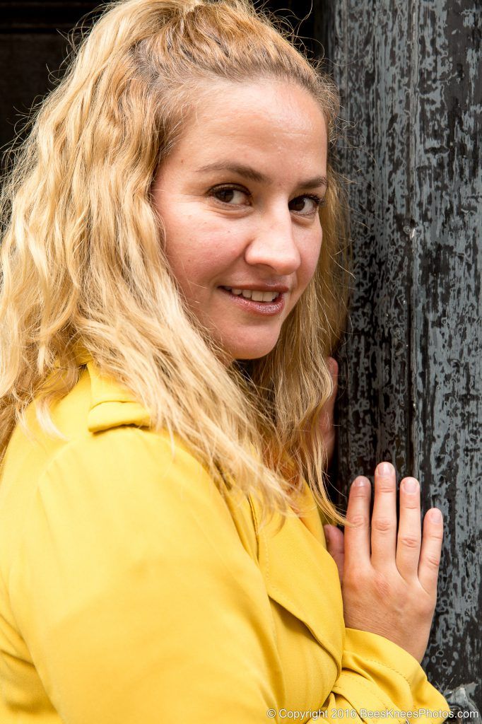 woman wearing a yellow coat leaning against a black door