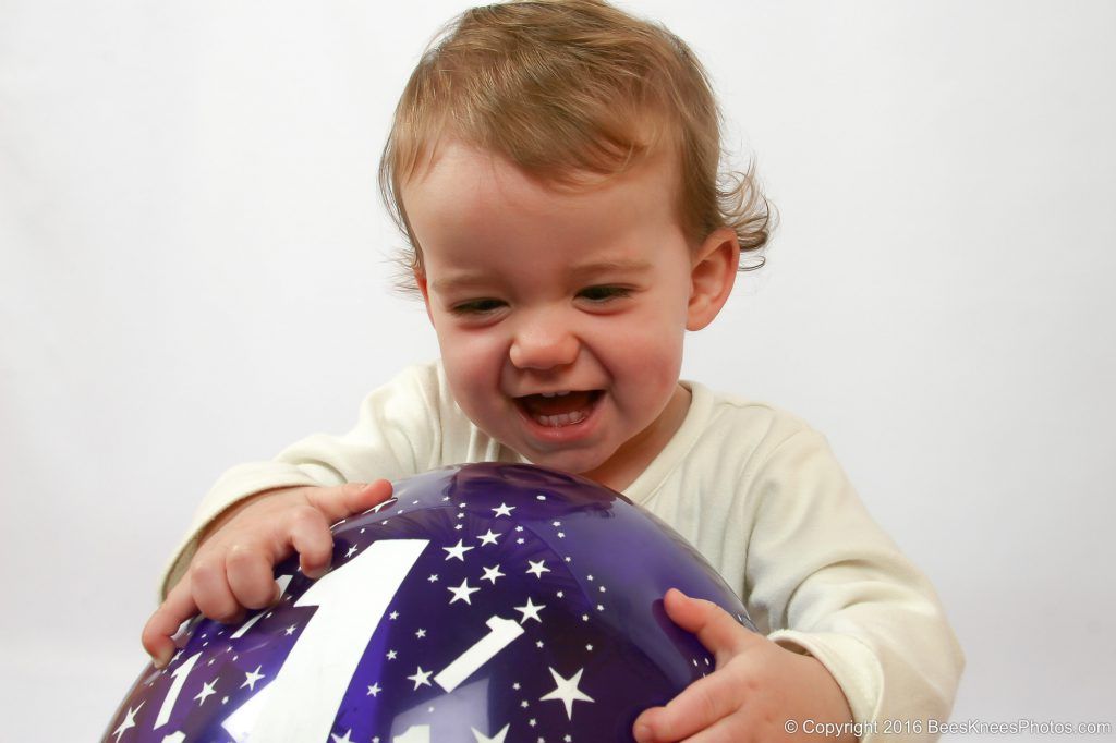 young girl playing with a balloon on her first birthday