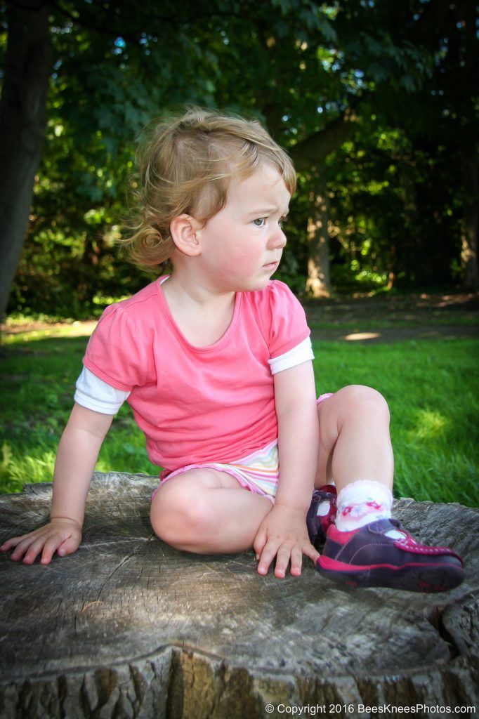 young girl sat on a tree stump in the park